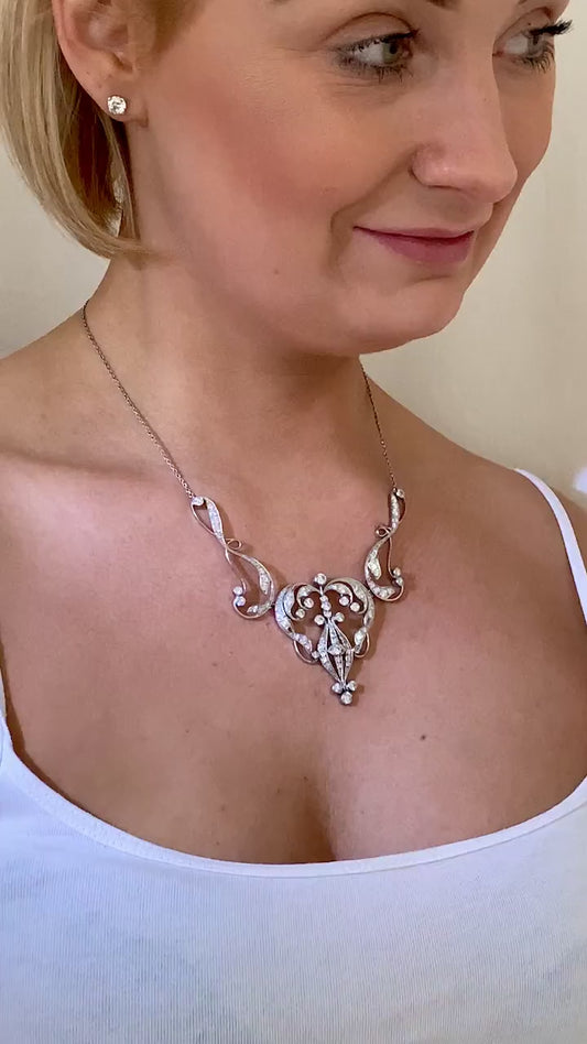 Early 20th Century three-part necklace. It has a stylized heart-shaped central panel between two scroll wing sections. The wing sections are set with a total of 26 diamonds totaling .95ct. The central panel contains 56 diamonds in total approximately. The overall diamond weight is 4.48ct approximately.